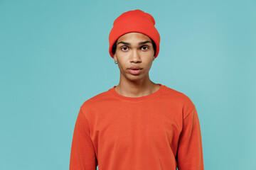 Young cool confident handsome stylish african american man 20s wearing red shirt hat look camera isolated on plain pastel light blue color background studio portrait. People autumn lifestyle concept.