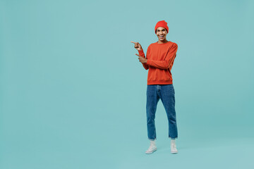 Fototapeta na wymiar Full body young happy african american man 20s wear orange shirt hat point index finger aside on wrokspace area isolated on plain pastel light blue background studio portrait People lifestyle concept