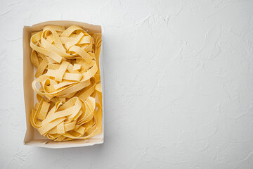 Raw pappardelle, on white stone table background, top view flat lay, with copy space for text