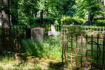 Silent summer day at churchyard old burial ground and fence in graveyard. Vintage grave with rusty...