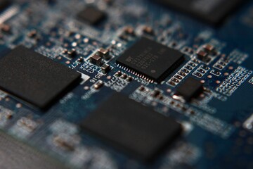 Circuit board close up of a turquoise board with black chips, narrow depth of field, blurry bokeh
