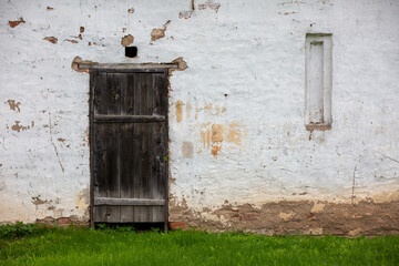 Fragment of white painted wall with Old wooden weathered door