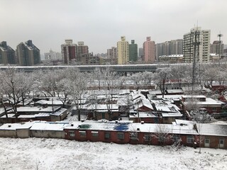 Fresh snowfall in Beijing, China; winter view of village, apartment buildings, and aboveground metro
