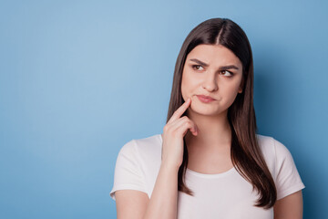Portrait of pretty minded unsure lady look empty space finger cheek on blue background