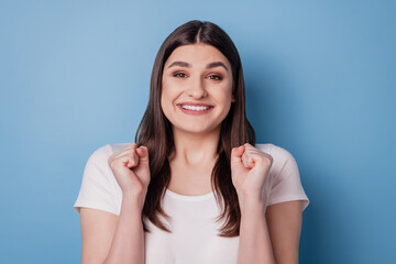 Portrait of astonished cheerful crazy winner lady raise fists celebrate victory on blue wall