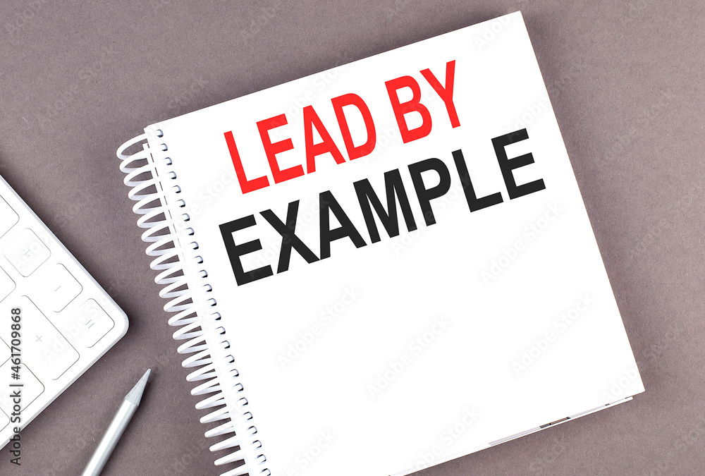 Poster lead by example text on the notebook with calculator and pen