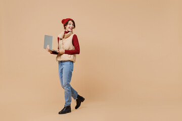 Full body side view young woman 20s wears red turtleneck vest beret hold use work on laptop pc...