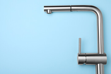 Modern pull out kitchen faucet on light blue background, top view. Space for text