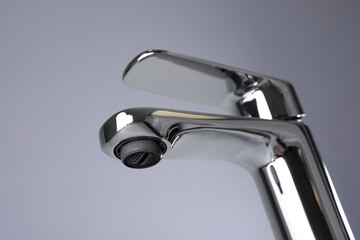 Single handle water tap on grey background, closeup