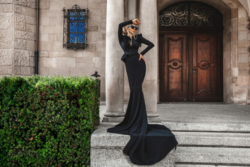 Elegant fashion. Young woman in elegant long dress on palace background. Fashion model in gown...