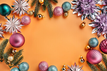 Overhead composition of Christmas background. Round frame made of shiny decorations on orange background with copy space