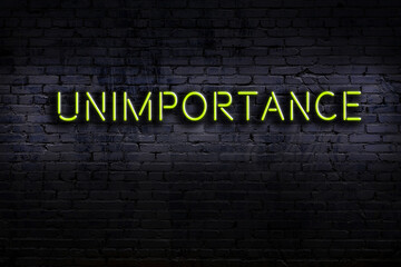 Neon sign. Word unimportance against brick wall. Night view - obrazy, fototapety, plakaty