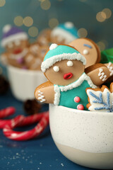 Delicious homemade Christmas cookies in bowl on blue wooden table against blurred festive lights, closeup