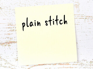 Yellow sticky note on wooden wall with handwritten word plain stitch