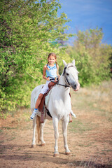 Schoolgirl girl rides a white pony. A child riding a horse