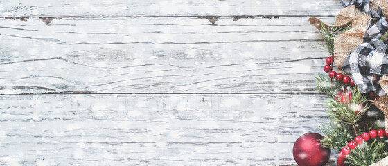 Top view of Christmas ornaments and trimmings against a white rustic table with snow flakes. Top view web banner.