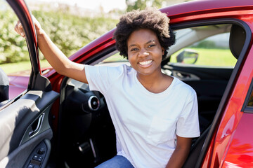 Young black woman sit on is first red car