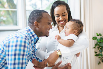 Happy parents with baby boy at home in the bedroom