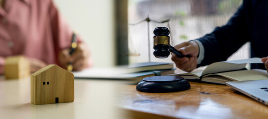 Real estate agent with attorney holding a hammer on finance approval concept to sign a lease Or buy a home with a home loan and home insurance in the office.