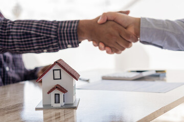 Fototapeta na wymiar A handshake between the sales representative and the landlord when signing a home purchase or renting contact at the workspace desk. A real estate agent or bank officer explains the interest on a loan