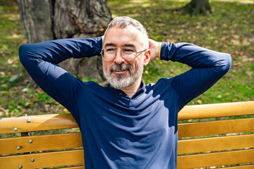 Portrait of a mature man sitting on a bench in an urban park