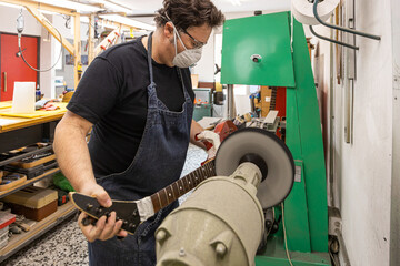 Focused man buffing guitar in workshop