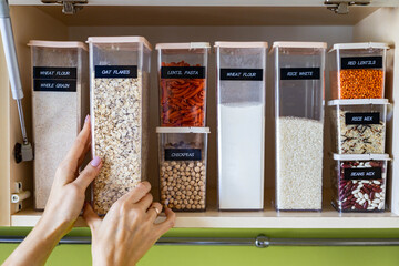 Storage pasta in boxes use Konmari method at wooden cupboard in kitchen. Placing, sorting, keeping