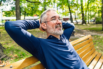 Portrait of a mature man sitting on a bench in an urban park