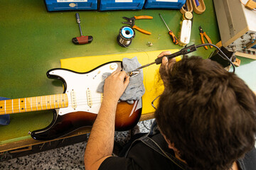 Unrecognizable man using screwdriver on guitar on table