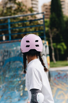 Cheerful African American woman in pink helmet and elbow pads