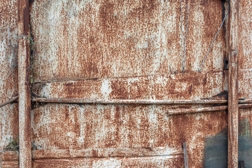 The rusty metal wall of the old garage as a natural background. The pattern and texture of rusted iron.