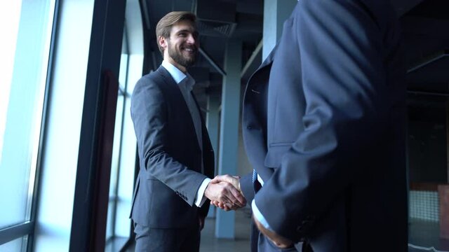 Two happy professional business men executive leaders shaking hands at office meeting