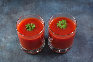 Two glasses with tomato juice on a blue grunge background. Flat lay.