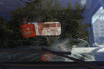 Crack patterns of shattered windshield on a driver's side. Macro shot of a broken window of the vehicle. Close up, copy space for text, background.