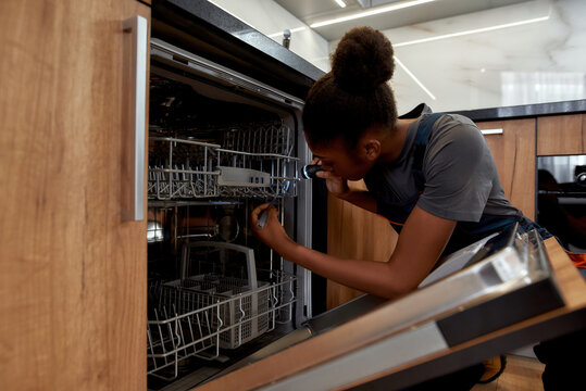 Maintenance service of home appliance. Female technician troubleshooting dishwasher