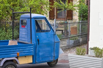 A traditional blue three-wheeled vehicle parked on the road (Tuscany, Italy, Europe) - 461728625