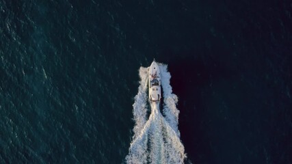 Top view on luxurious white yacht cruising in blue ocean waters in slow motion. Aerial drone shot of group of friends have party on deck of fancy sail boat