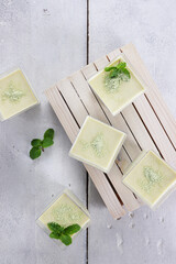 Green Tea Pana cotta in a glass decorated with mint leaf.