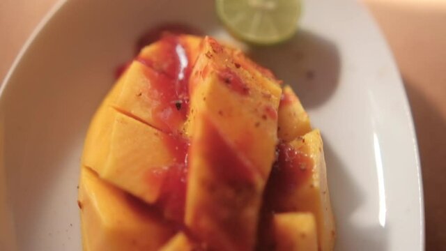 Plate of chopped mango with Mexican chamoy sauce and blurry background