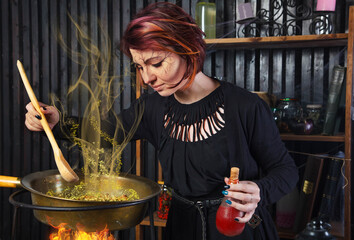 Young beautiful witch preparing a potion for Halloween 