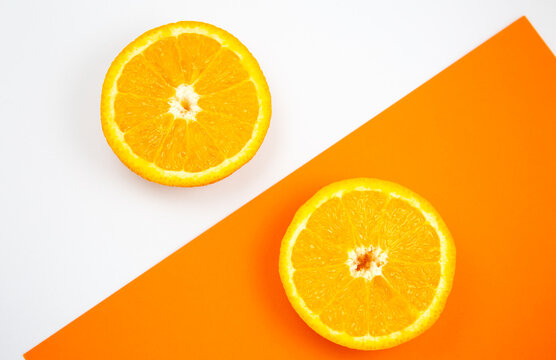 Close up photo of Orange Fruit on the white and orange background. Citrus cut in half, inside, macro view. Minimalism, original and creative image. Beautiful natural wallpaper.