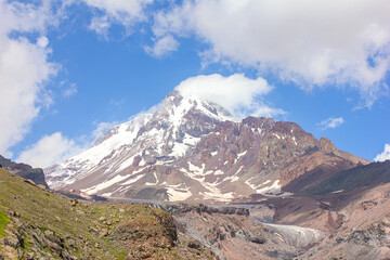 Mountain landscape with clouds and snow. View of Kazbek in the clouds from the Gergeti glacier