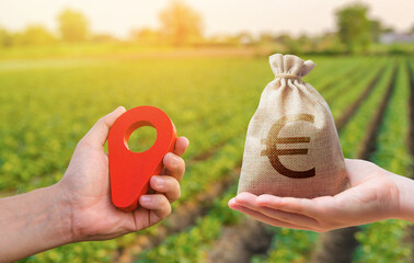 Hands with location pin and euro money bag. Land market. Buying and selling land. Estimation cost...