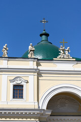 Fototapeta na wymiar Green dome with a cross and a roof with sculptures against the blue sky