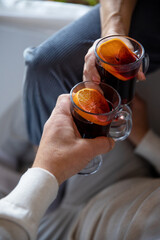 female and male hands holding glasses of mulled wine