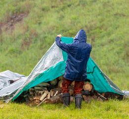 A man shelters firewood from the rain.