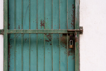 The rusty green iron door of a warehouse with white plaster flap