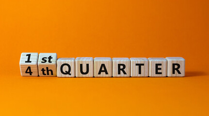 From 4th to 1st quater symbol. Turned wooden cubes and changed words '4th quater' to '1st quater'. Beautiful orange table, orange background. Business, happy 1st quater concept, copy space.