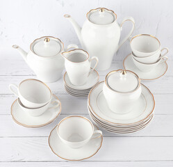 Porcelain tea set with gold border. Coffee pot, sugar bowl, cups, milk jug, saucers and plates. Service for 6 persons
