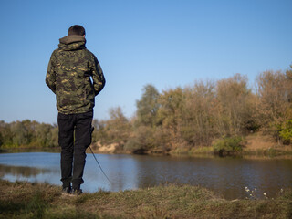 A young man is a fisherman with a spinning rod. Autumn fishing, outdoor activities and hobbies